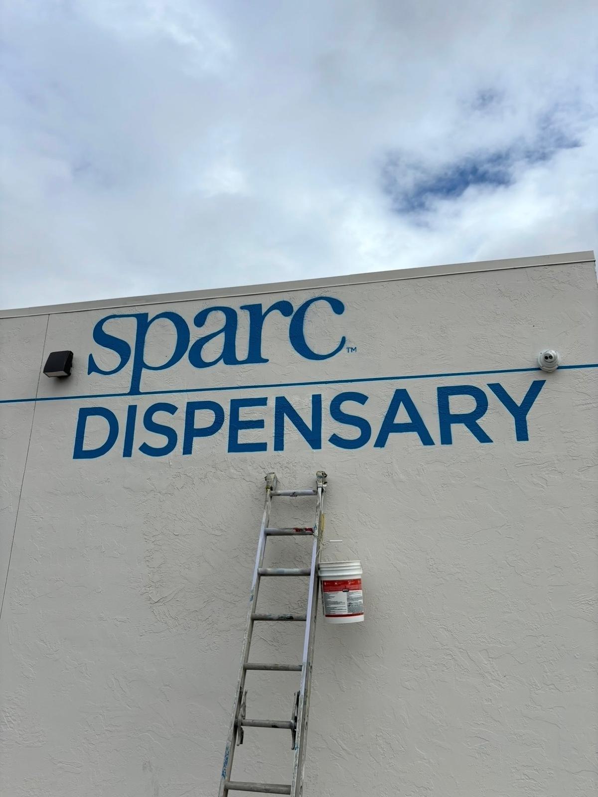 Completed blue Sparc Dispensary lettering and graphics on a white commercial exterior