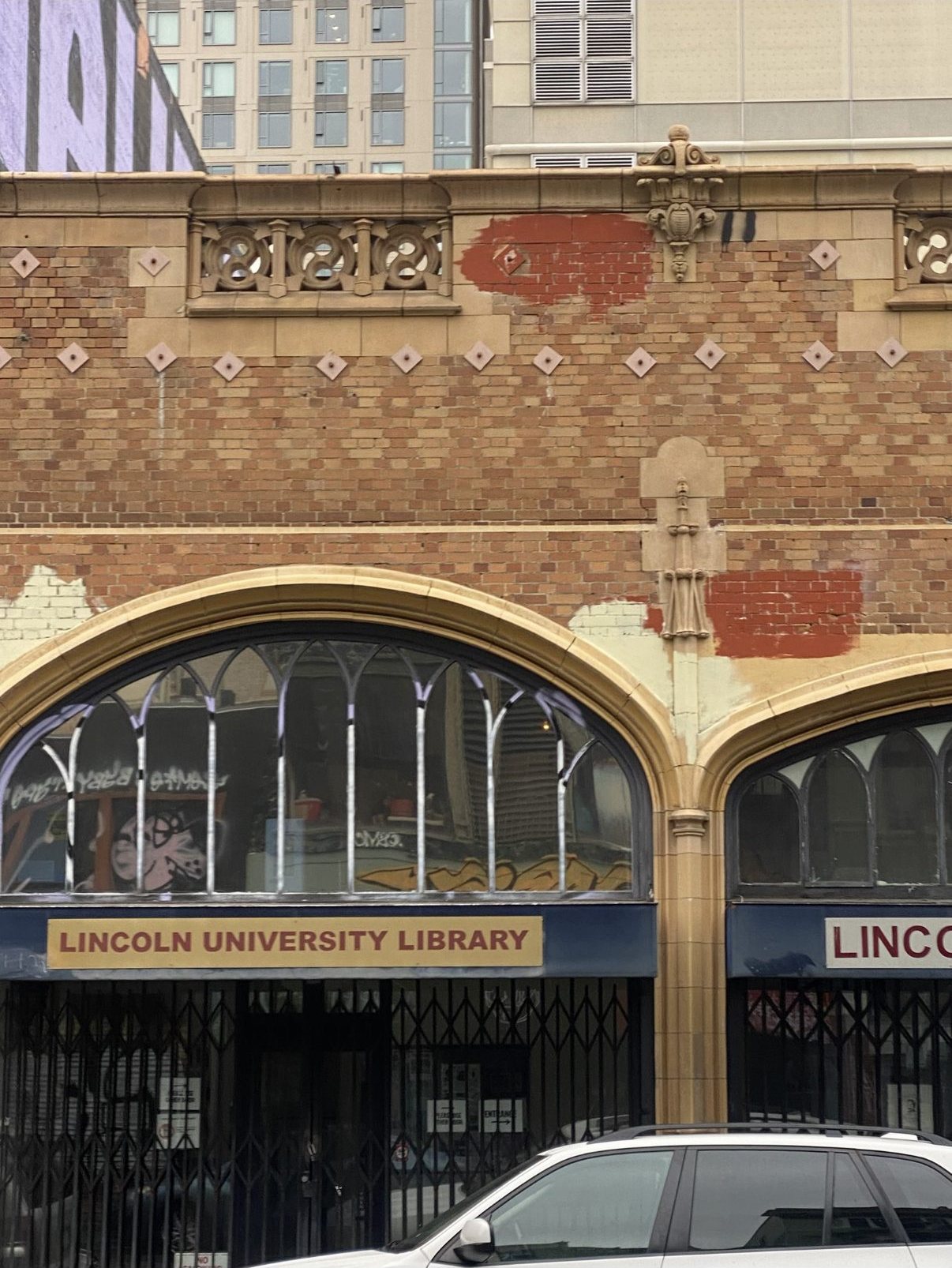 Mismatched paint patches covering graffiti on the Lincoln University Library brick façade