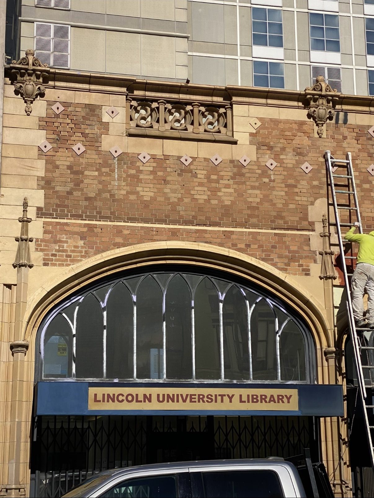 Worker removing graffiti and cover-up paint from the Lincoln University Library façade
